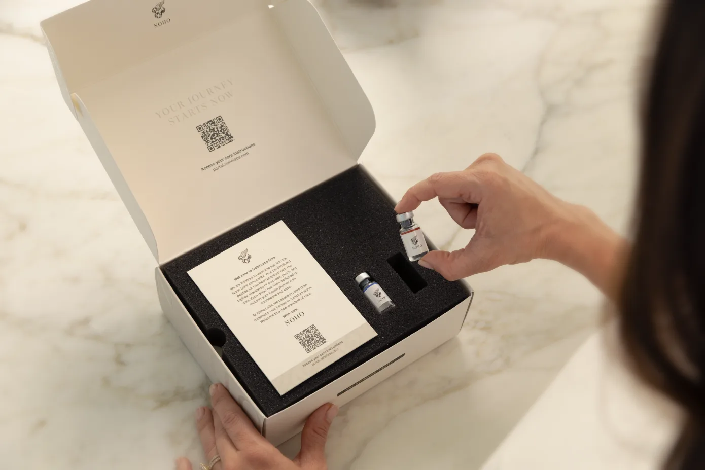 Hand lifting a vial from an open NOHO protocol box